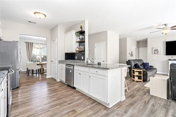Granite counters and stainless steel appliances adorn this kitchen with a seamless flow into the living area.