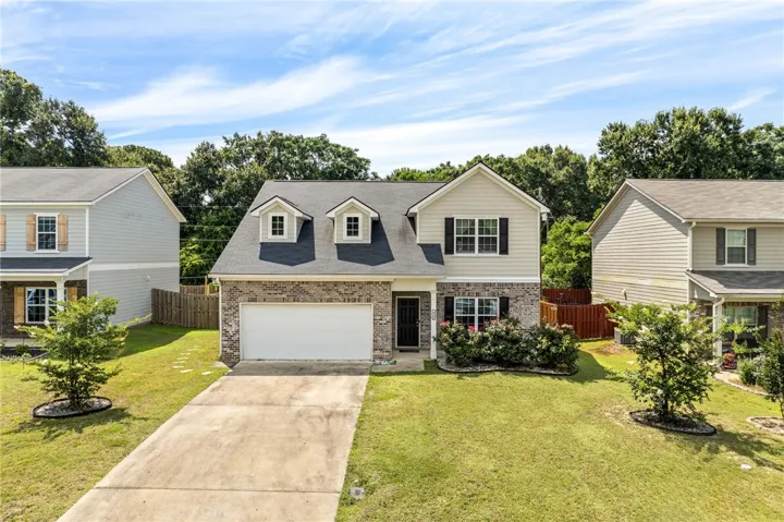 A classic brick and siding residence with a welcoming lawn and a spacious driveway.