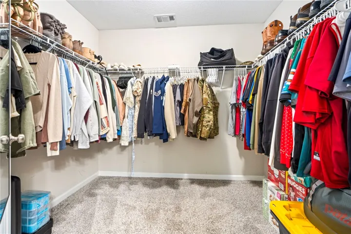 Walk-in closet with ample wire shelving and plush carpeting for comfortable storage.