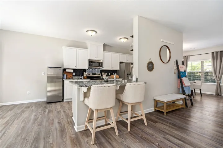 A well-appointed kitchen features a granite island with breakfast bar seating and stainless steel appliances.