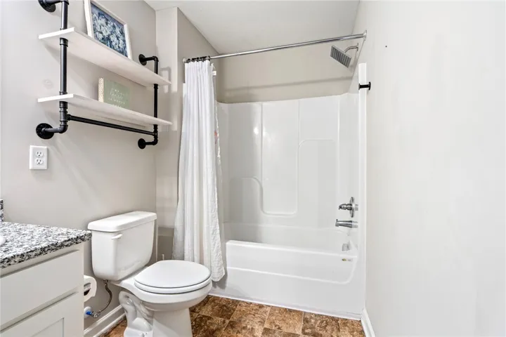 A well-appointed bathroom offers a convenient shower-tub combination and functional open shelving.