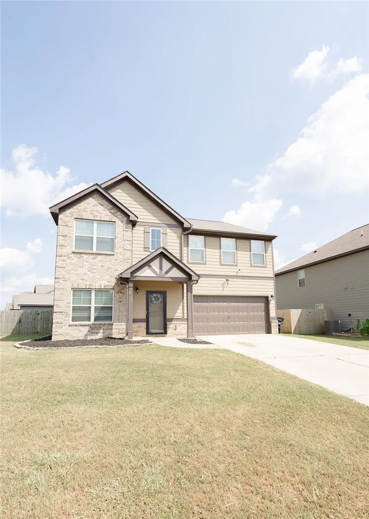 A classic two-story home featuring a welcoming covered entry and an attached garage.