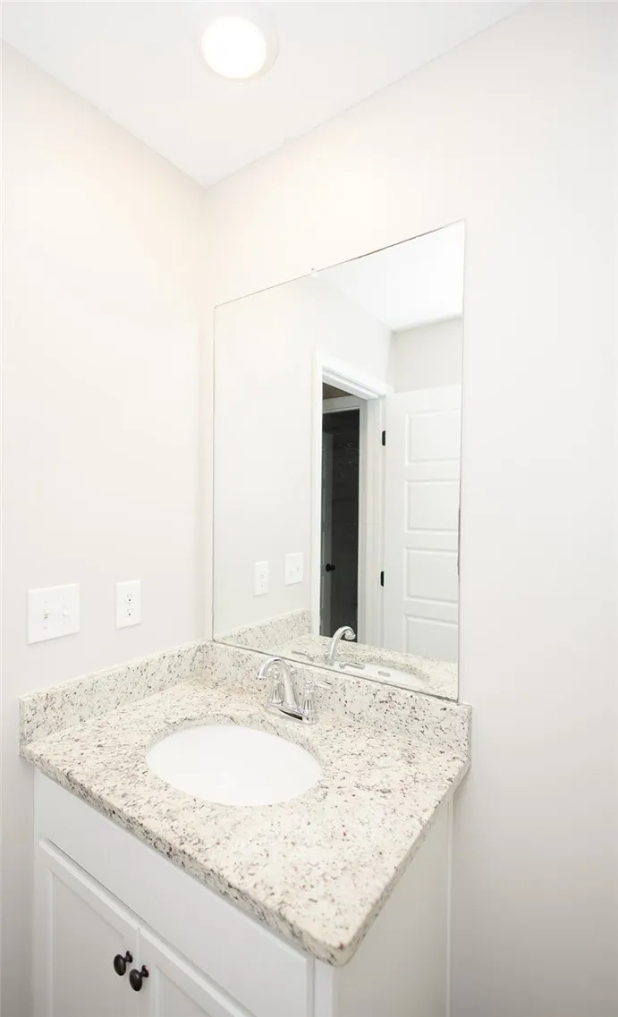 A well-appointed bathroom features a single vanity with granite counters and a large mirror.