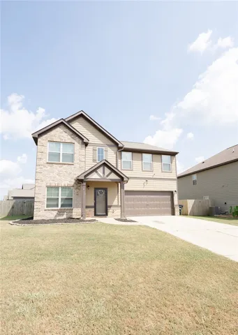 A classic two-story home featuring a welcoming covered entry and an attached garage.