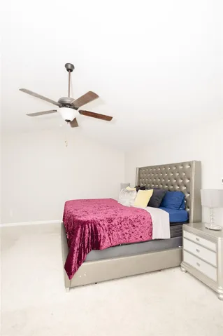 The ample primary bedroom offers lofty vaulted ceilings and comfortable carpet flooring, creating a serene personal retreat.