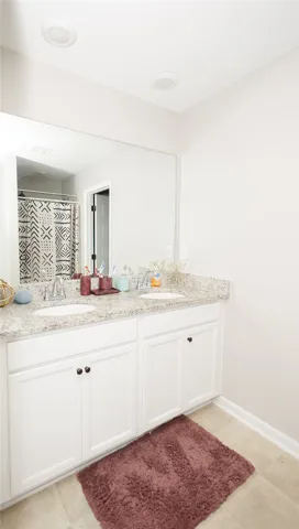 Double vanity with stone counters provides ample space in this well-appointed bathroom.
