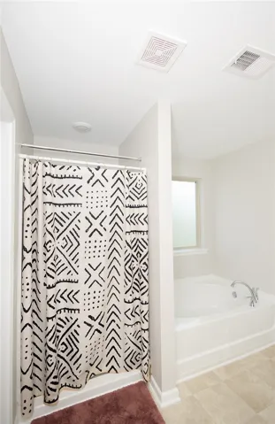 A well-lit bathroom provides a comfortable bathing experience with both a tub and shower option.