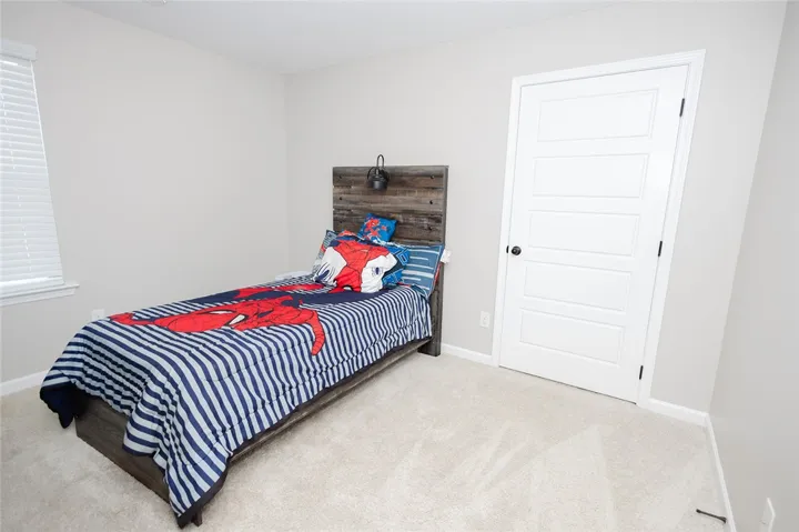 A well-lit bedroom features plush carpeting and a classic paneled door, ready for personalization.