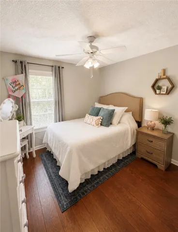 Rich hardwood floors complement this cozy bedroom with a ceiling fan for year-round comfort.