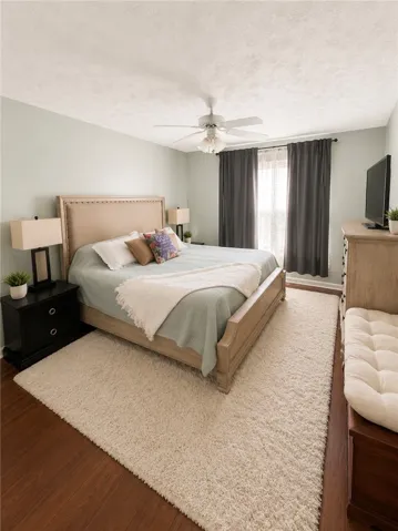 A tranquil bedroom retreat features rich hardwood floors and a cozy, large area rug, promising restful nights.