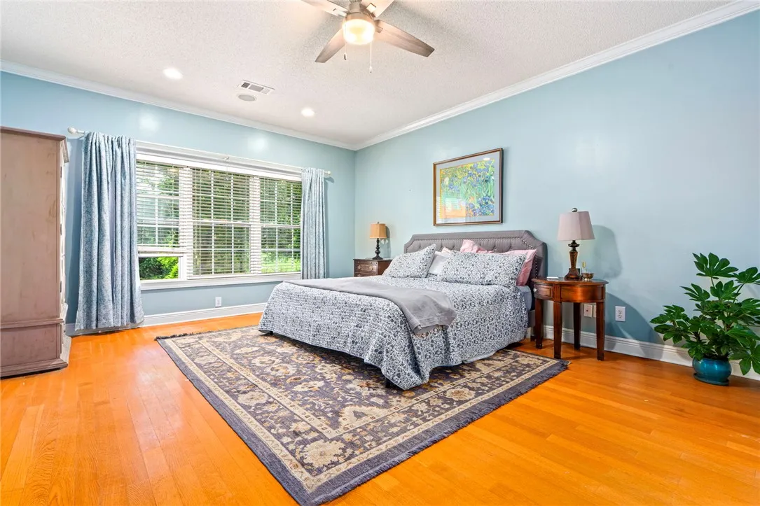 Hardwood floors and a large window illuminate this airy bedroom, perfect for unwinding.