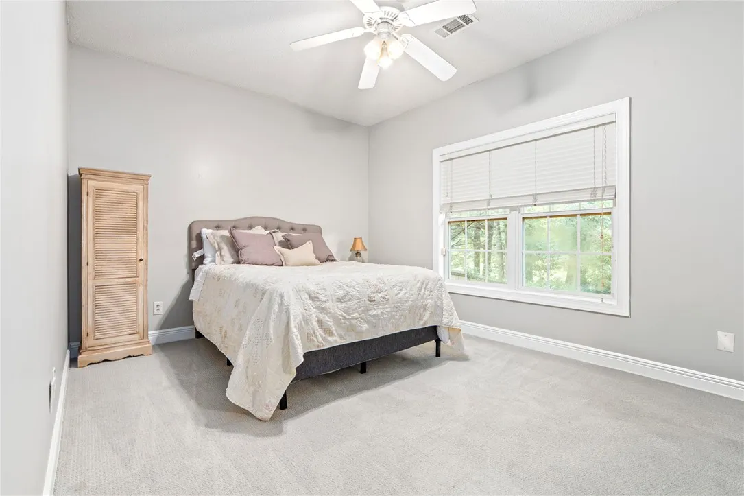 A tranquil sleeping space featuring a large window and plush carpeting.