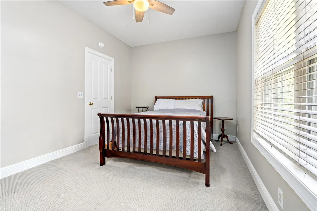 A comfortable bedroom featuring soft carpeted floors and a ceiling fan for year-round comfort.