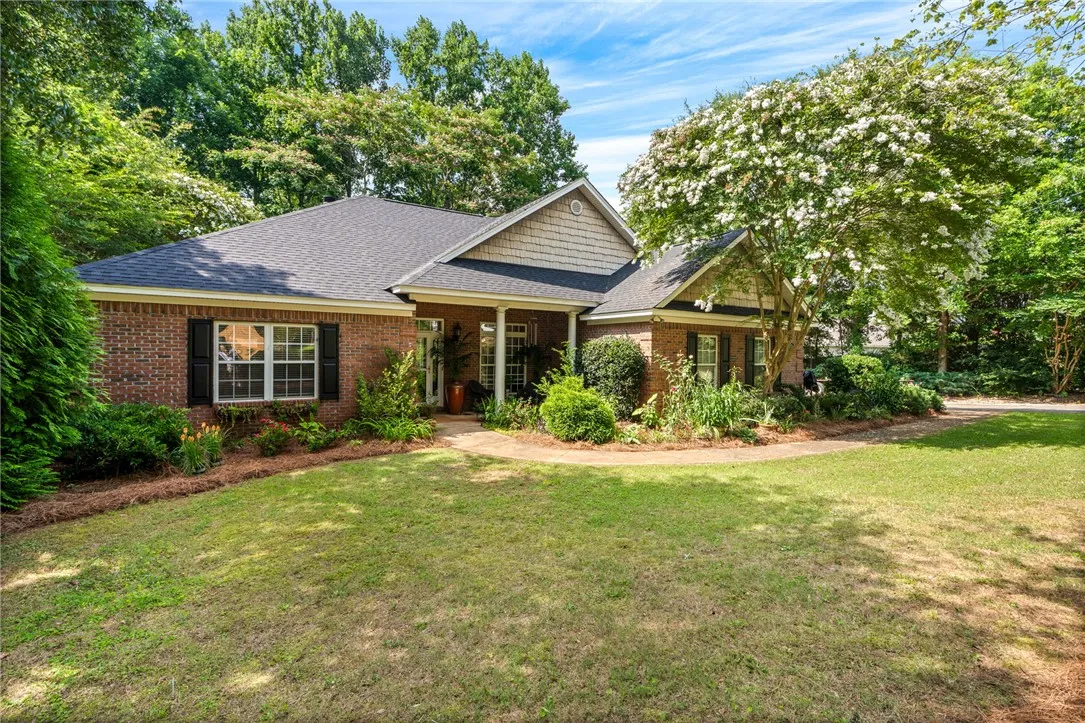 A well-maintained brick residence is surrounded by verdant landscaping, offering exceptional curb appeal.