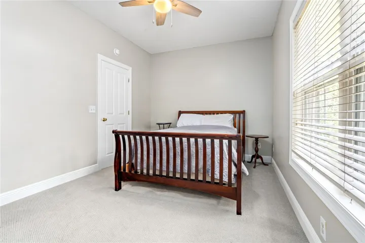A comfortable bedroom featuring soft carpeted floors and a ceiling fan for year-round comfort.