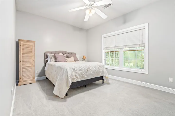 A tranquil sleeping space featuring a large window and plush carpeting.