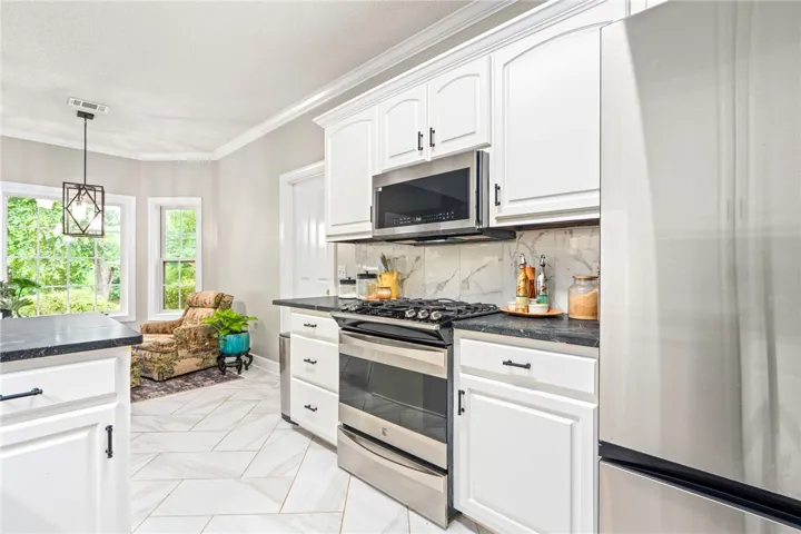 A contemporary kitchen space boasts gleaming white cabinetry and stainless steel appliances.