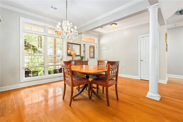 Grand chandelier lighting illuminates this warm dining space with polished wood flooring.