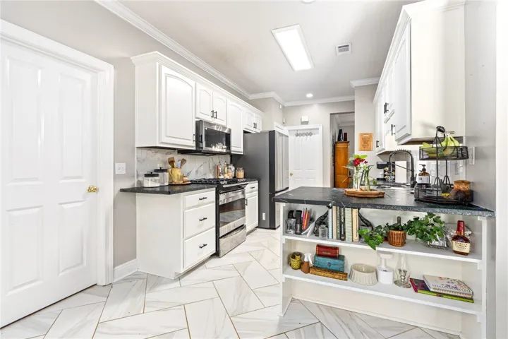 White cabinetry, sleek soapstone countertops, and modern appliances outfit this highly functional kitchen.
