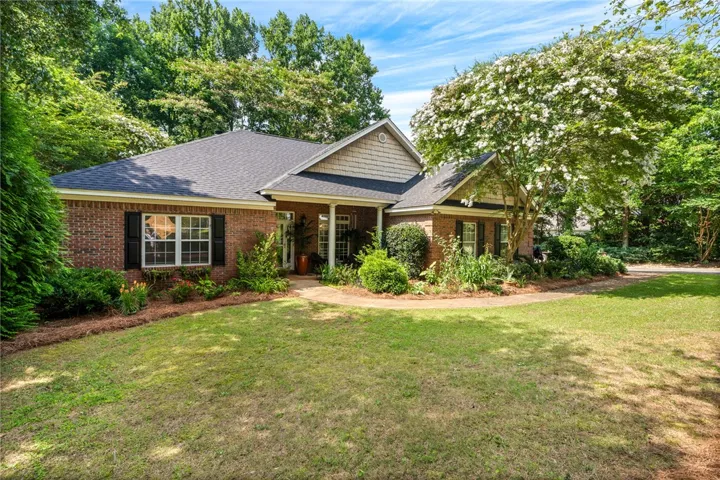 A well-maintained brick residence is surrounded by verdant landscaping, offering exceptional curb appeal.