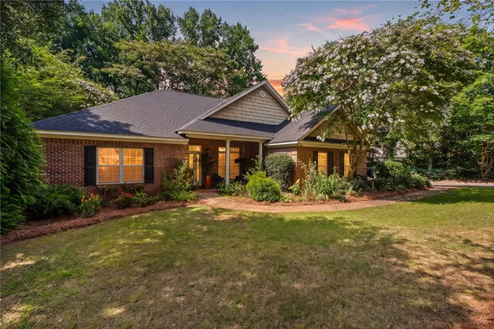 A classic brick exterior with a welcoming front entrance, framed by mature trees and verdant landscaping.