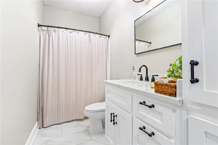 White vanity with dark fixtures offers a clean, modern aesthetic in this well-appointed bath.