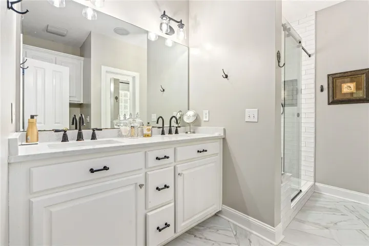 Marble-patterned flooring elevates this bathroom's dual vanity and bright shower.