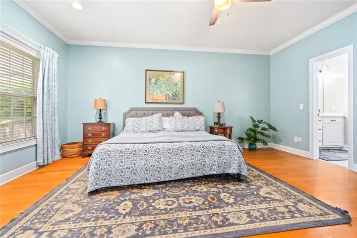 Hardwood flooring flows through this primary bedroom, offering comfort and direct access to an en-suite bath.