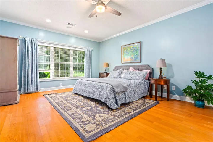 Hardwood floors and a large window illuminate this airy bedroom, perfect for unwinding.