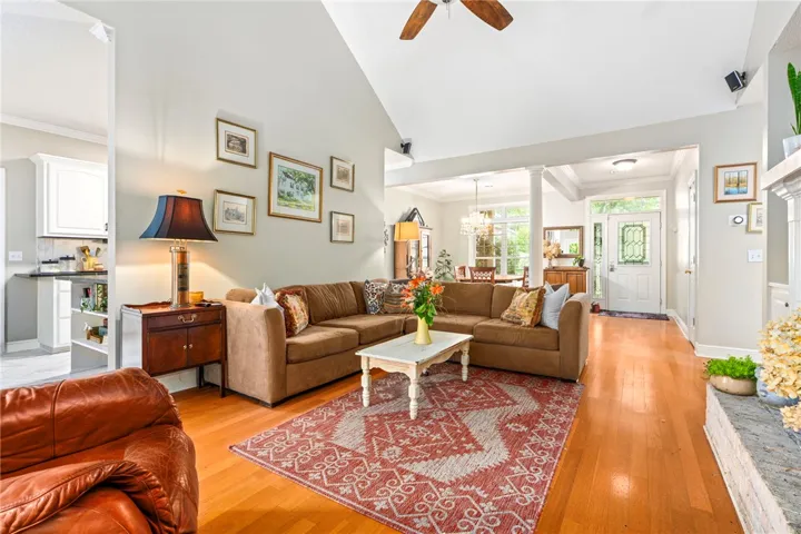 Natural light pours into this living space, featuring high ceilings and warm wood flooring.