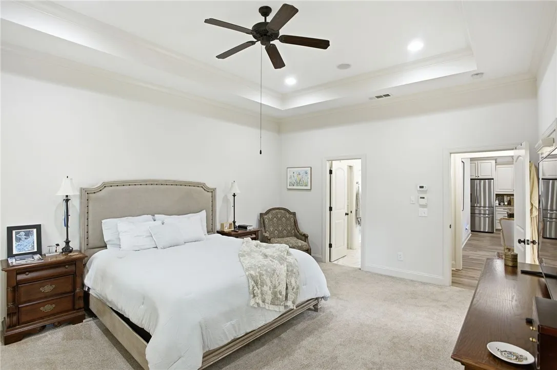 A spacious bedroom features a ceiling fan, recessed lighting, and soft carpeting.