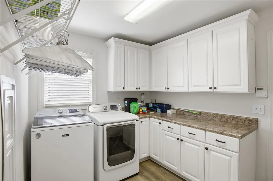 A well-appointed utility room features abundant white cabinetry and durable countertops, ready for household tasks.