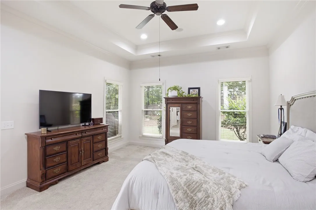 A restful bedroom with abundant natural light features a tray ceiling and a soothing neutral palette.