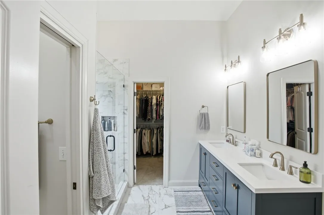Marble tile flooring and double vanity create a luxurious bathroom oasis leading to a spacious walk-in closet.