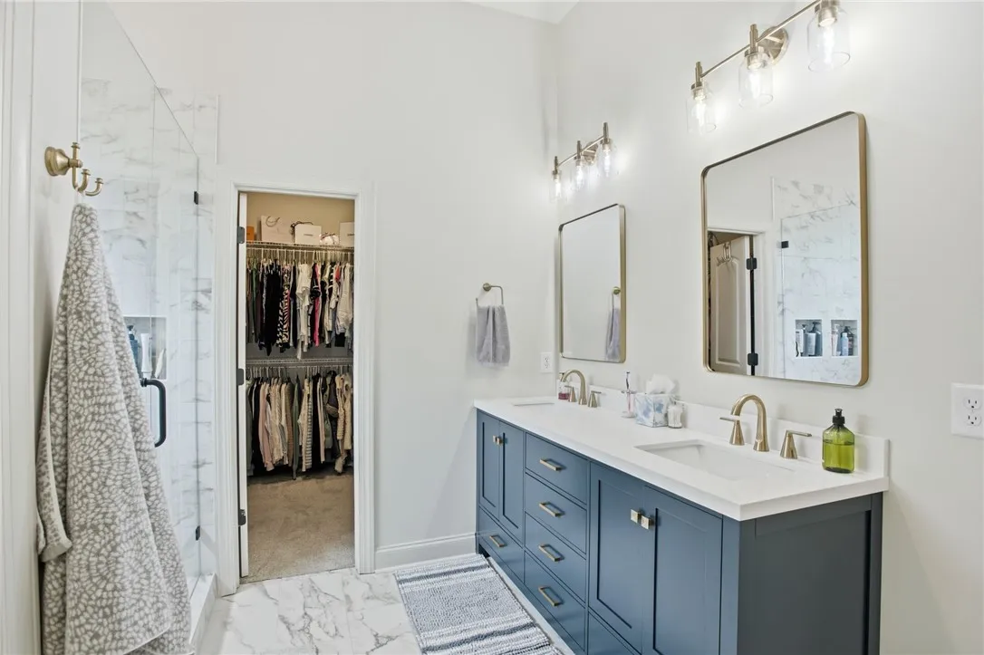Marble-look flooring and white walls complement the sleek vanity and dual sinks, offering a seamless blend of modern style and functionality.