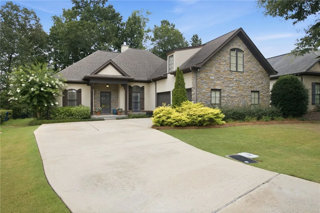A graceful stone and stucco exterior welcomes with a sweeping driveway and manicured plantings, offering elegant curb appeal.
