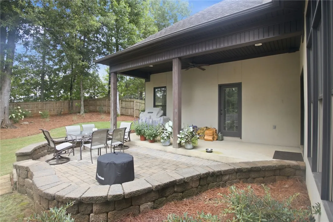 An inviting covered patio with a fire pit and dining area offers serene outdoor living.