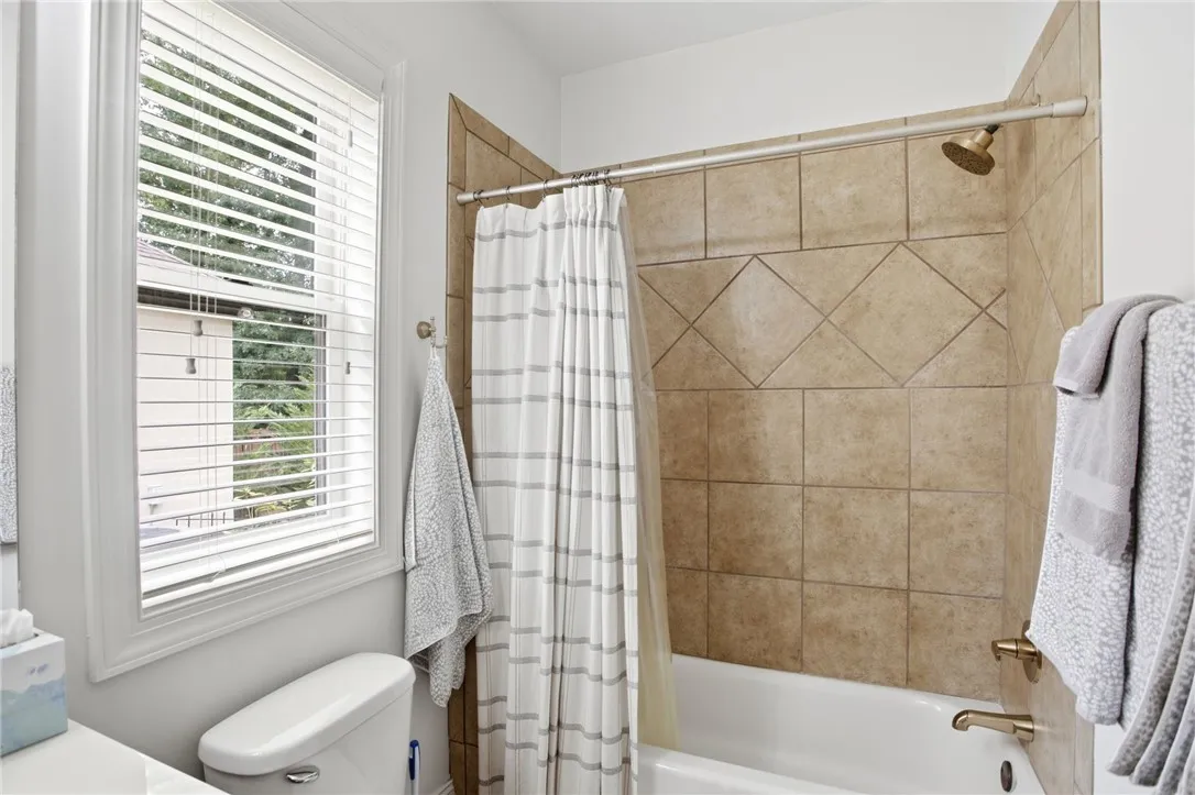 A well-appointed bathroom features a tile-surrounded tub and shower combination with a window providing natural light.