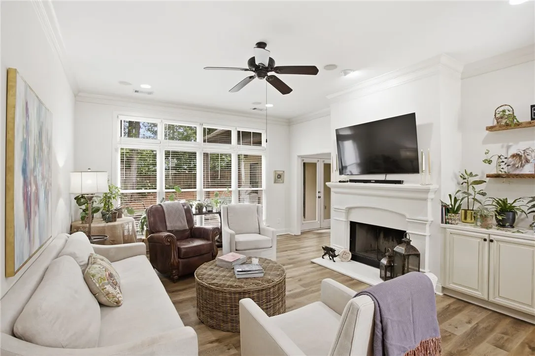 Sun-filled living space features a cozy fireplace, abundant windows, and durable hardwood flooring.