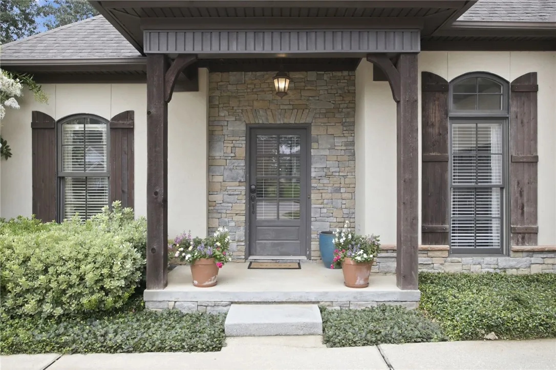 A welcoming stone and stucco facade greets visitors with a charming covered porch entry.