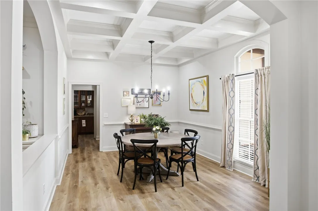 Ornate coffered ceilings and hardwood flooring elevate this formal dining space, complete with a statement chandelier.