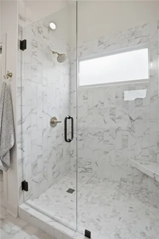 A sleek, tiled shower with a frameless glass enclosure offers a contemporary bathing experience.