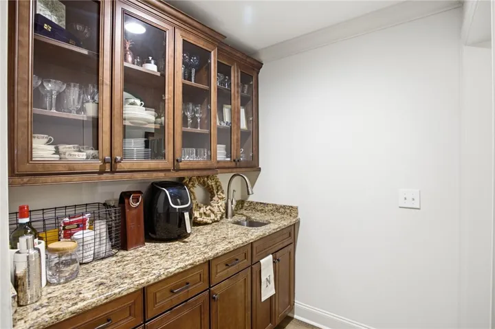 A wet bar features granite counters and glass-front upper cabinetry for entertaining ease.