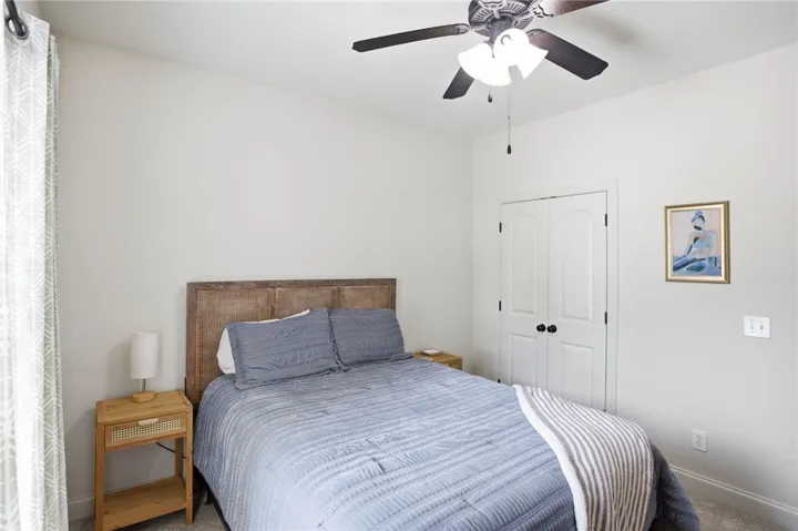 An inviting bedroom with plush carpeting and a convenient ceiling fan.