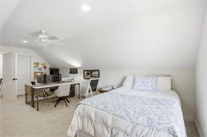 Cozy attic bedroom with sloped ceilings and plush carpeting, perfect for relaxation or a dedicated workspace.