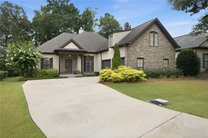 A graceful stone and stucco exterior welcomes with a sweeping driveway and manicured plantings, offering elegant curb appeal.
