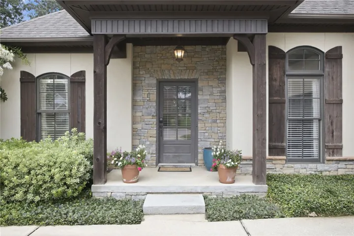 A welcoming stone and stucco facade greets visitors with a charming covered porch entry.