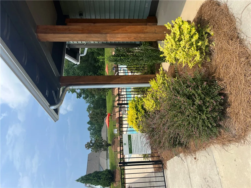 Lush landscaping frames the entry to a vibrant community pool area.