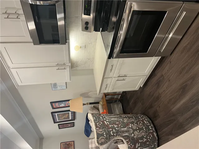 A compact kitchen area with sleek stainless steel appliances and wood-look flooring.