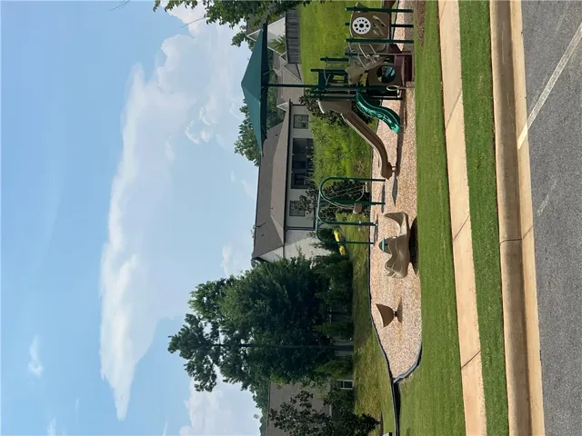 A community playground awaits, featuring modern equipment set on a wood chip surface, ready for recreation.